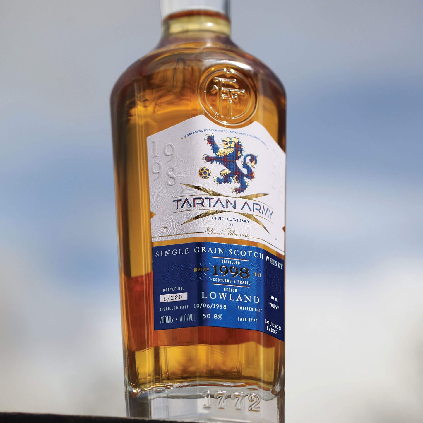 Lifestyle image of bottle of Tartan Army Lowland Whisky on grey background